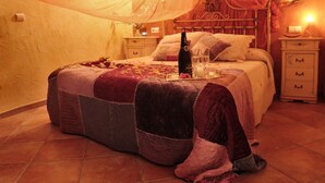 A bedroom with a canopy bed, a bedside table with a bottle and glasses, and a nightstand with a lamp. - romantic house for 2 people with jacuzzi (Laroya)