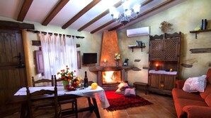 A cozy living room with a fireplace, wooden furniture, and a television. - romantic house for 2 people with jacuzzi (Laroya)
