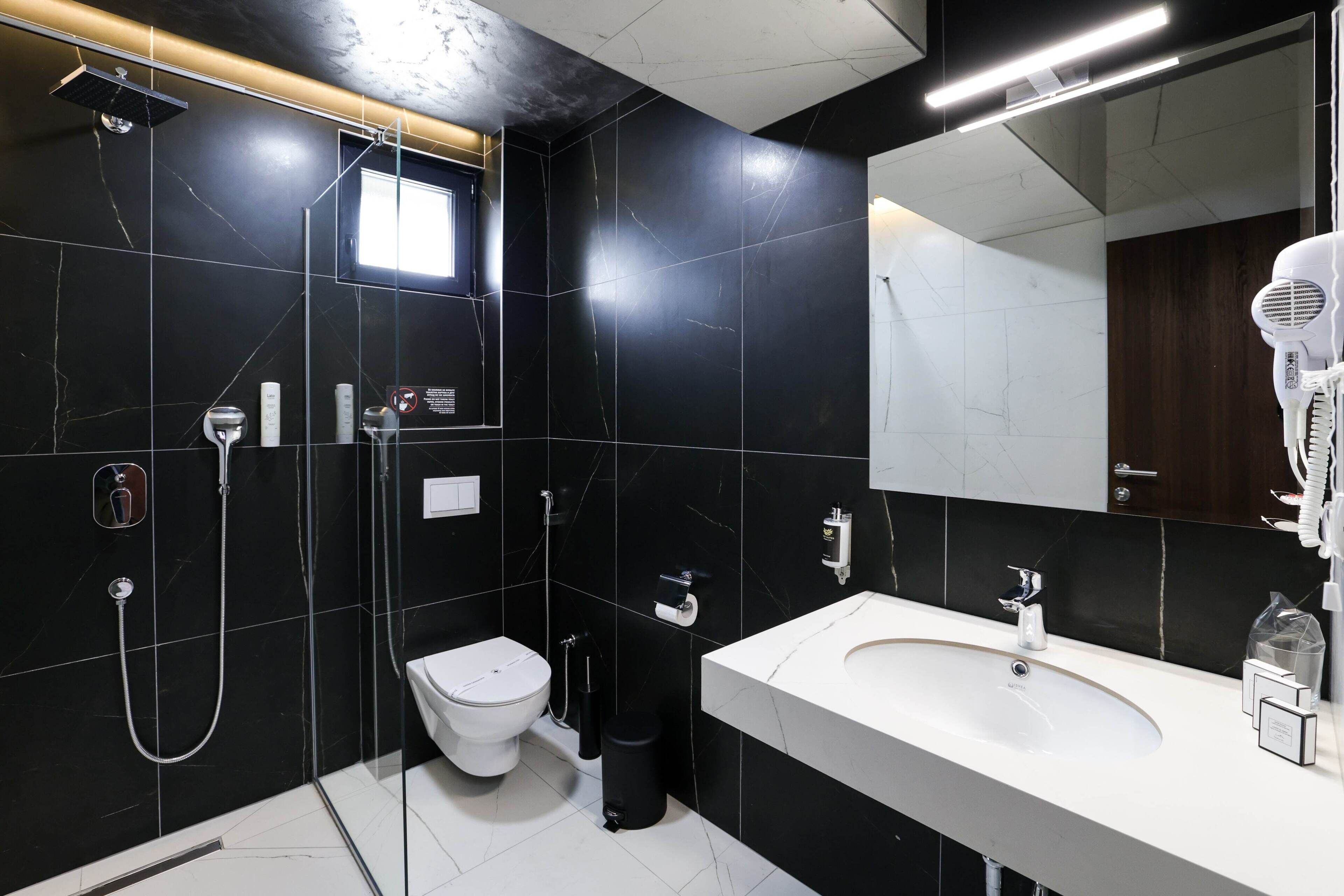 Een moderne badkamer met een zwart betegelde muur, een wit wastafelmeubel en een handdroger.
