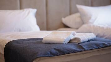 A neatly made bed with a folded white towel and a dark blue blanket.
