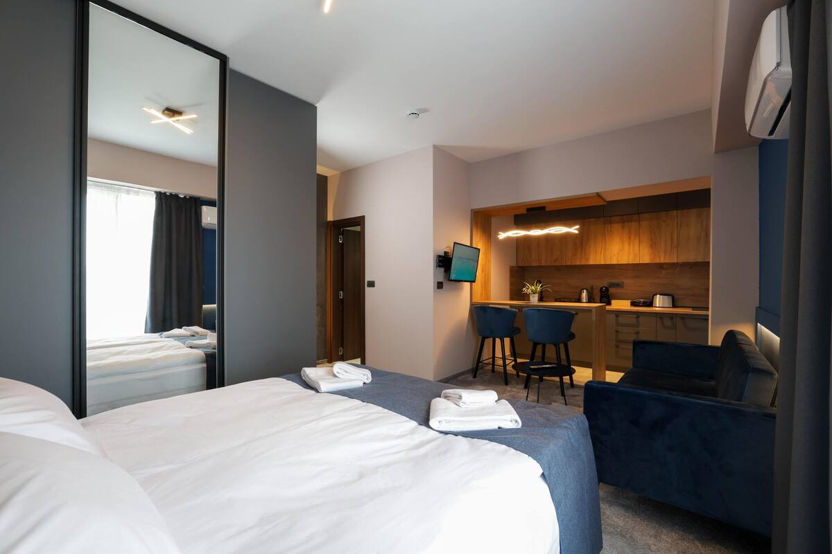 A hotel room with a large bed, a desk, and a kitchenette.