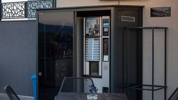 Un kiosque en libre-service doté d’une interface numérique, d’une poubelle et d’une table avec des chaises.