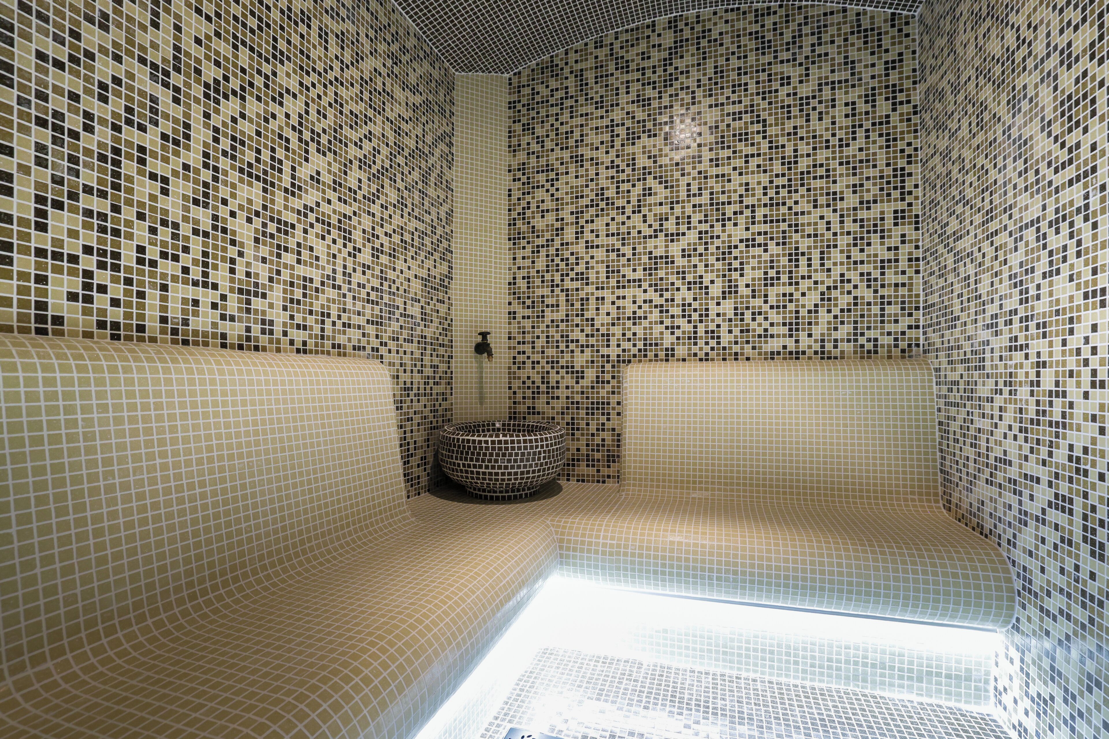 A bathroom with mosaic tile walls and a curved bench.