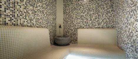 A bathroom with mosaic tile walls and a curved bench.