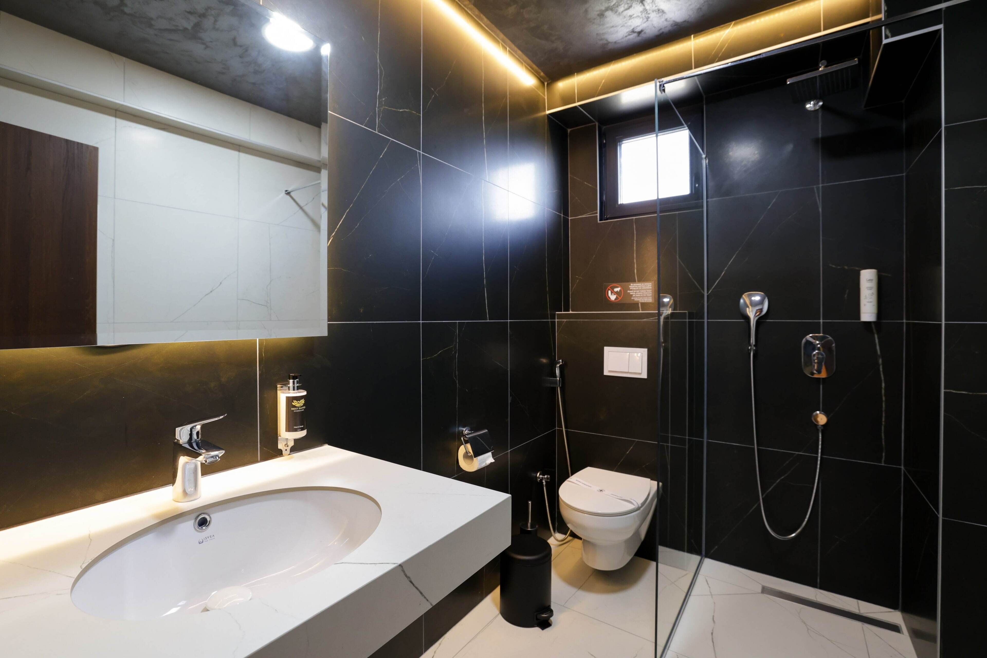 A modern bathroom with a large white sink, a toilet, and a shower area.