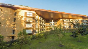 Un edificio a più piani con tetto piatto e un cortile alberato.