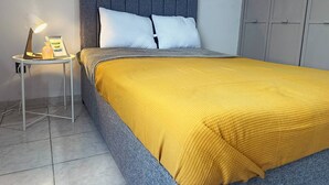 A neatly made bed with a grey headboard and a yellow blanket, a small bedside table with a lamp, and a framed motivational quote. - Depa Privado 2 Hab 5p Santa Tere (Guadalajara)