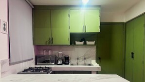 A kitchen with green cabinets, a white countertop, a gas stove, a microwave, a coffee maker, and a sink. - Depa Privado 2 Hab 5p Santa Tere (Guadalajara)
