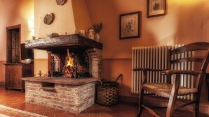 Una habitación acogedora con chimenea, una silla de madera, un radiador y un tapete estampado.