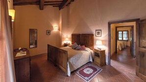 Un dormitorio con techo de madera, una cama con cabecera, mesitas de noche con lámparas y un espejo en la pared.