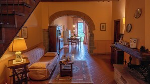 Una sala de estar acogedora con una escalera de madera, un sofá, una mesa con lámpara y una chimenea.