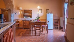 Una cocina acogedora con suelo de baldosas, muebles de madera, una lámpara colgante y un refrigerador.