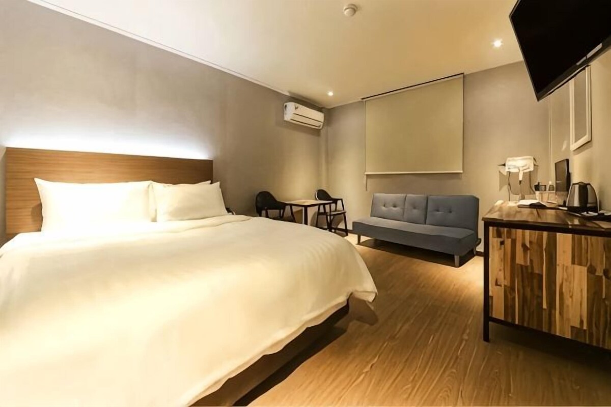 Une chambre d’hôtel avec un grand lit, un canap é, un bureau et un téléviseur à écran plat.