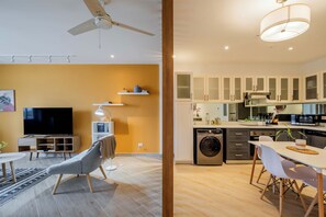 A modern apartment with a living area featuring a flat-screen TV, a ceiling fan, and a dining area with a table and chairs. - w* | Luxury 1BR in Casco Antiguo w/ Balcony & View (Panamá)