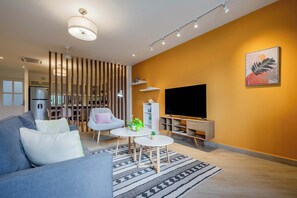 Un salon moderne avec un canapé, un téléviseur, une table basse et une plante décorative.