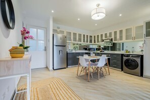 A modern kitchen with white cabinets, stainless steel appliances, and a dining area with a round table and chairs.