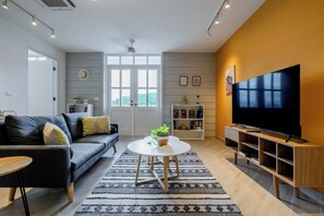 A modern living room with a sofa, coffee table, TV, and bookshelf.