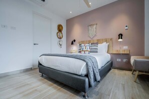 Une chambre à coucher moderne, avec un lit, des tables de chevet, une lampe fixée au mur et un ventilateur de plafond.