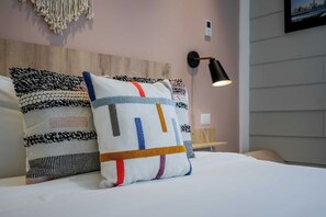 A bed with two decorative pillows, a wall-mounted lamp, and a macrame wall hanging. - w* | Luxury 1BR in Casco Antiguo w/ Balcony & View (Panamá)