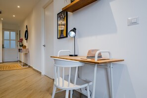 A modern room with a wooden desk, white chairs, a framed artwork, a floor lamp, and a small table with a basket. - w* | Luxury 1BR in Casco Antiguo w/ Balcony & View (Panamá)