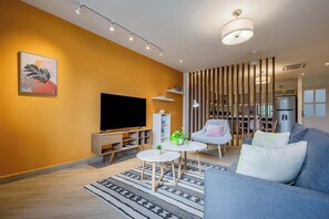 Un salon moderne avec un téléviseur à écran plat, un canapé, une table basse et une plante décorative.