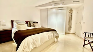 A bedroom with a bed, bedside table, lamp, wardrobe, and a hanging decoration.