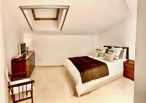Un dormitorio con cama, mesita de noche, cómoda y escritorio con silla.