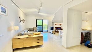 A modern living room with a sofa, TV, and dining area.