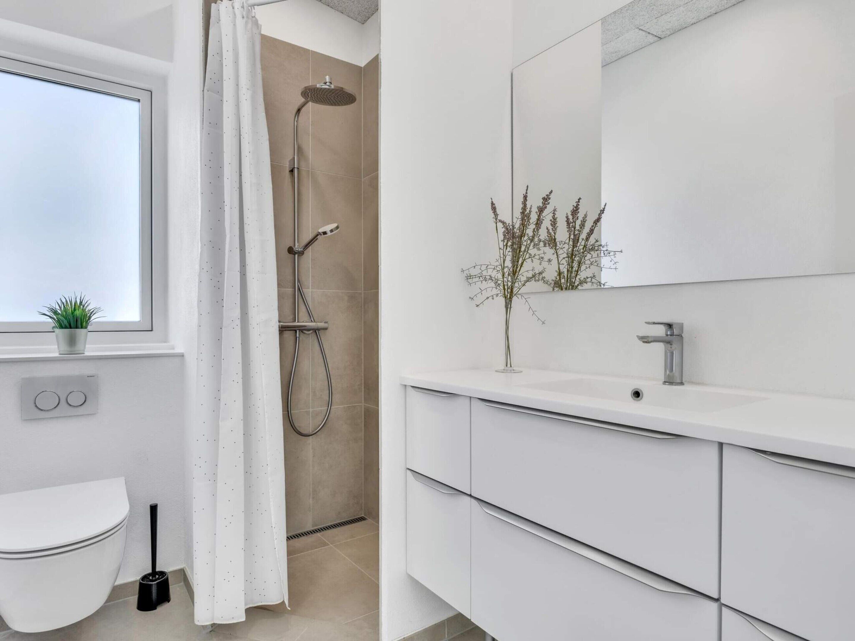 A modern bathroom with a shower, toilet, and sink.