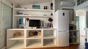 Eine moderne Küche mit weißen Schränken, einem eingebauten Fernseher und einem Kühlschrank.