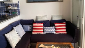 Ein Wohnzimmer mit einem dunkelblauen Sofa, gestreiften Kissen und einem Holztisch mit zwei Tassen.