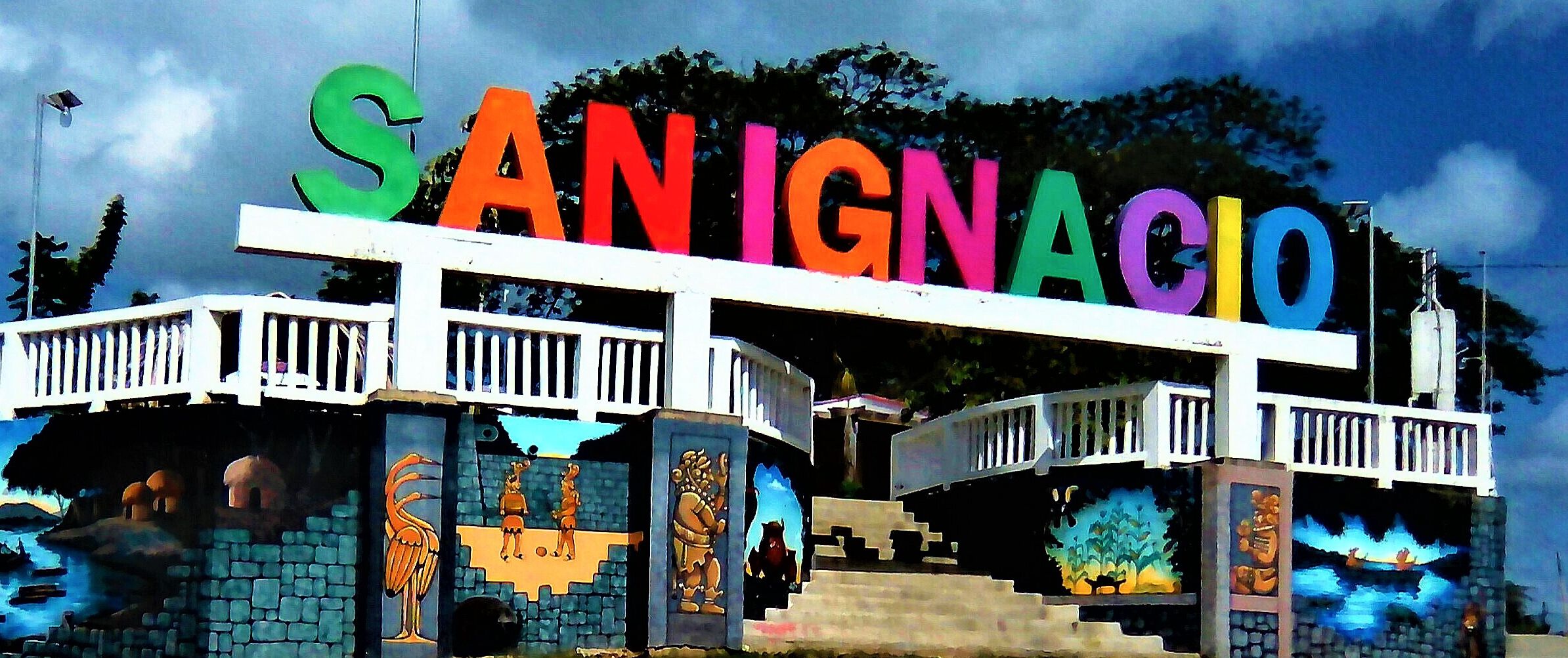 A colorful sign with the name "SAN IGNACIO" above a building with a balcony and steps leading up to it.