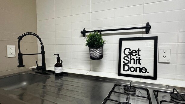 A kitchen with a stainless steel sink, a faucet, a gas stove, a potted plant, and a motivational sign. - Spacious 8-Bedroom House in Central Guadalajara (Guadalajara)