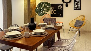 A dining area with a wooden table set for four, surrounded by chairs, a large plant, and artwork on the walls. - Spacious 8-Bedroom House in Central Guadalajara (Guadalajara)