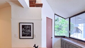 A kitchen with a wooden countertop, a black cabinet, a framed quote on the wall, and a window with a view of greenery. - Spacious 8-Bedroom House in Central Guadalajara (Guadalajara)