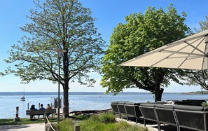 Et siddeområde ved søen med udsigt over vandet, et træ og en bænk.
