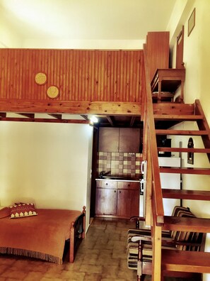 Un dormitorio estilo loft con techo de madera y escalera empotrada.