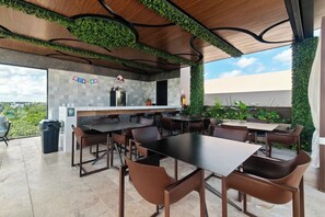 An outdoor dining area with tables and chairs, a kitchen counter, and a view of greenery. - Vibra Bonito Luxe Boho-chic Hideaway in Tulum (Tulum)