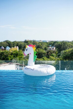 A swan-shaped inflatable in a swimming pool with a clear view of a residential area in the background. - Vibra Bonito Luxe Boho-chic Hideaway in Tulum (Tulum)