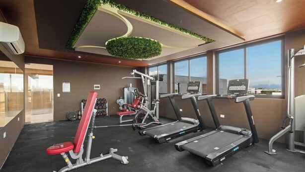 A gym with treadmills, weight machines, and a large window with a city view.