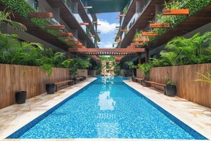 A pool with a tiled floor, surrounded by wooden benches and potted plants. - Vibra Bonito Luxe Boho-chic Hideaway in Tulum (Tulum)