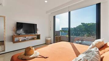 Un dormitorio con una cama grande, un televisor en la pared y un balcón con vistas.