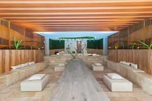A modern indoor space with a long central seating area, wooden walls, and a stone floor. - Vibra Bonito Luxe Boho-chic Hideaway in Tulum (Tulum)