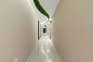 A long, narrow hallway with a reflective floor and a green, leafy ceiling feature.