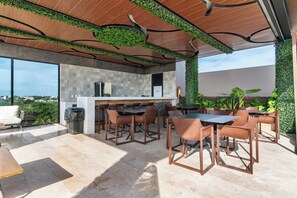 An outdoor kitchen area with a bar, seating, and a view of the city.