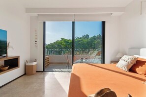 A modern bedroom with a large bed, a television, and a balcony with a view of trees. - Vibra Bonito Luxe Boho-chic Hideaway in Tulum (Tulum)