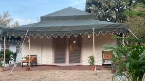 A tent with a porch, a bench, and potted plants. - Kumbh Travel (Prayagraj)