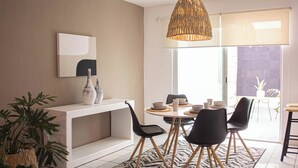 A modern dining area with a white console table, black chairs, a round table with bowls and cups, and a hanging wicker light fixture. - Charming House Rental in Zapopan, Mexico - Your Private Oasis (Zapopan)