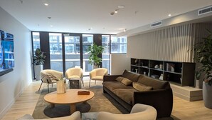 Een moderne woonkamer met een bank, stoelen, een salontafel en een open haard.