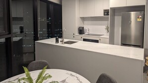 Een moderne keuken met een centraal eiland, roestvrijstalen apparatuur en een eetgedeelte met een marmeren tafel.